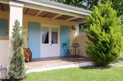 a blue house with a white door and two trees at Auberge Clermont in Franschhoek