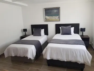 two beds in a room with white and gray sheets at Arcangeli Wines in Botrivier
