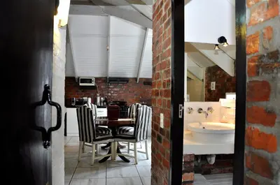 a dining room with a table and a sink at Los Olivos at the Yard in Franschhoek