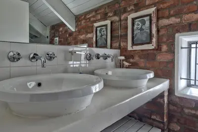 a bathroom with two sinks and a brick wall at Los Olivos at the Yard in Franschhoek