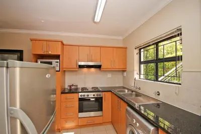 a kitchen with wooden cabinets and a stainless steel refrigerator at Vilaroux in Stellenbosch