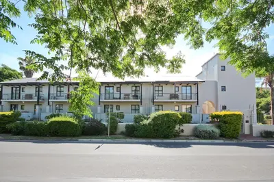 an apartment building with bushes in front of a street at Vilaroux in Stellenbosch