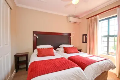 a bedroom with two beds with red pillows at Vilaroux in Stellenbosch