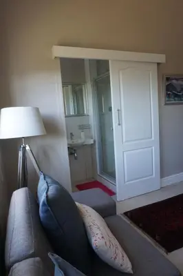 a living room with a couch and a door to a bathroom at 5 Pierre Jourdan in Franschhoek