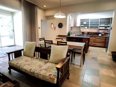 a living room with a couch and a table and a kitchen at Laanhof Victorian House Self-Catering in Stellenbosch