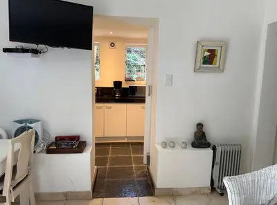 a kitchen with white walls and a television on the wall at Olive Tree Garden apartment 1 in Cape Town