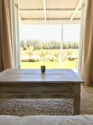 a wooden table in a room with a large window at Olive Cottage in Franschhoek