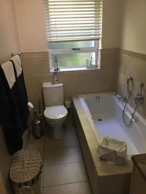 a bathroom with a tub and a toilet and a window at The Blue Marine Self-Catering in Gordonʼs Bay