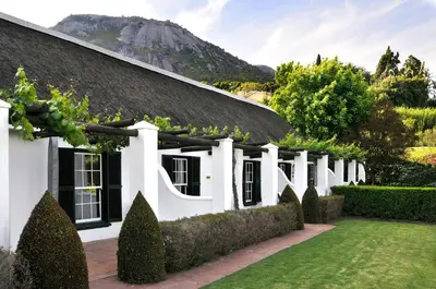 an exterior view of a white house with a garden at Grande Roche Hotel in Paarl