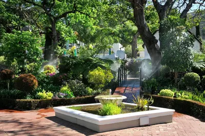 a garden with a water fountain in a park at Grande Roche Hotel in Paarl