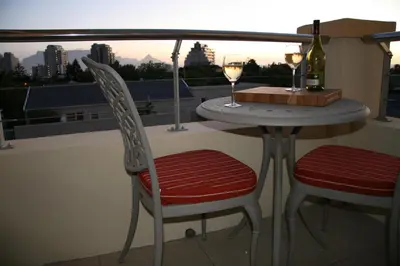 a table with two chairs and two glasses of wine at Freshhh in Bloubergstrand