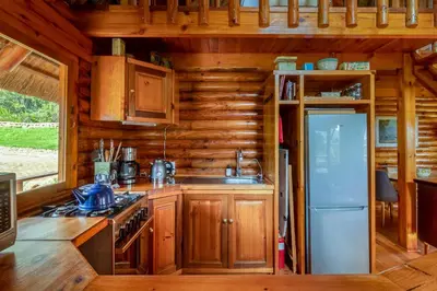 a kitchen with wooden cabinets and a refrigerator at Tulbagh Mountain Cabin in Wolseley