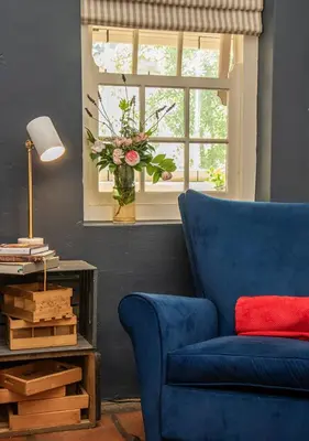 a blue couch and a window with a vase of flowers at Via's Guesthouse in Greyton