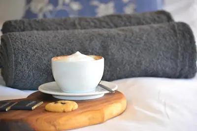 a cup of coffee on a wooden tray on a bed at Via's Guesthouse in Greyton