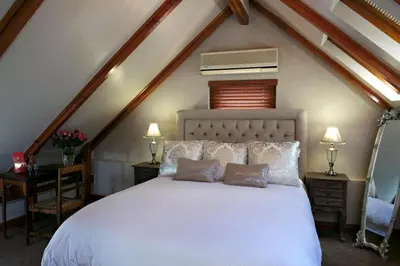 a bedroom with a white bed with two tables and two lamps at Roosenwijn Guesthouse in Stellenbosch