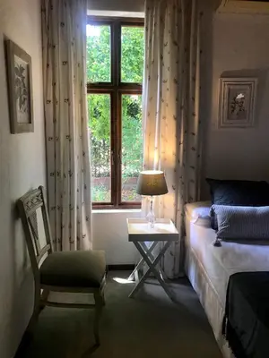 a bedroom with a bed and a chair and a window at At Home in Mostertsdrift in Stellenbosch
