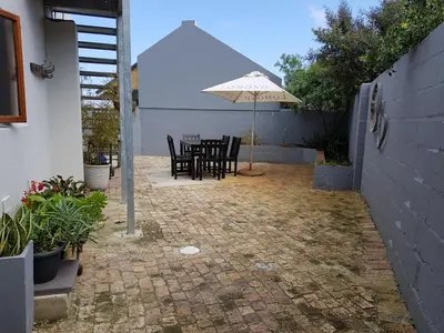 a patio with a table and an umbrella at Hemel en Aarde Village Accommodation in Hermanus
