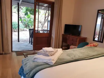 a bedroom with a bed and a tv and a window at Hemel en Aarde Village Accommodation in Hermanus
