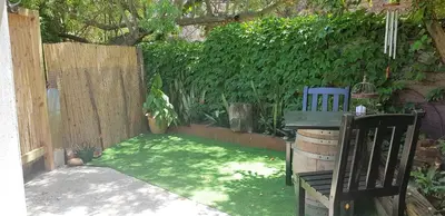 a small garden with a chair and a fence at Hemel en Aarde Village Accommodation in Hermanus