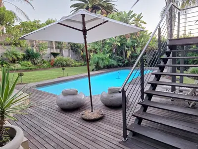 an umbrella sitting on a deck next to a pool at Eversview Guesthouse in Durbanville