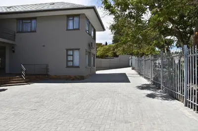 a white house with a fence and a driveway at 34onlincoln Guesthouse in Bellville