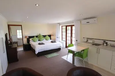 a bedroom with a large bed with green pillows at Acara Guesthouse & Cottages in Stellenbosch
