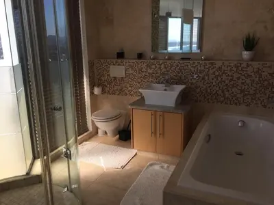 a bathroom with a tub and a sink and a toilet at Hibernian Towers 1802 Self Catering Accommodation Strand Western Cape South Africa in Strand