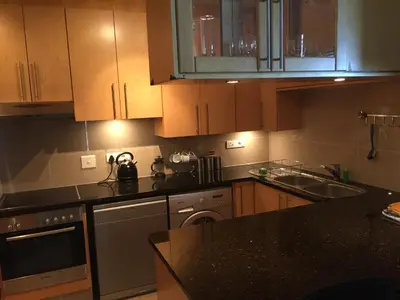 a kitchen with wooden cabinets and a black counter top at Hibernian Towers 1802 Self Catering Accommodation Strand Western Cape South Africa in Strand
