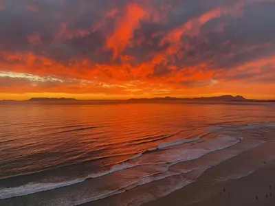 a sunset on the beach with the ocean at Ocean View 505 Self Catering Accommodation Strand Western Cape South Africa in Strand