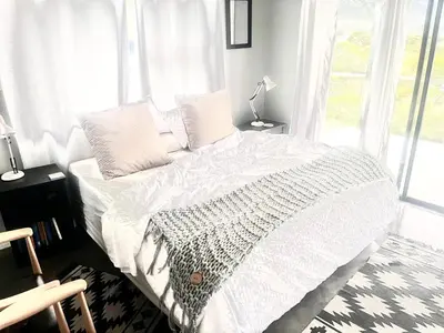 a bedroom with a bed with white sheets and a window at 3 Indigo with Solar in Hermanus