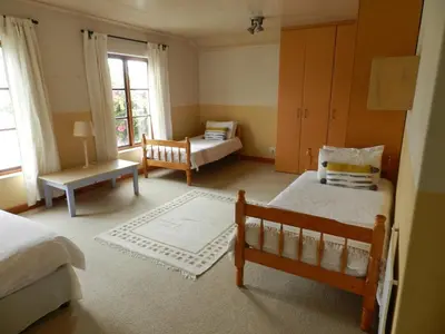a bedroom with two beds and a chair in it at Sunset at Diluta in Cape Town