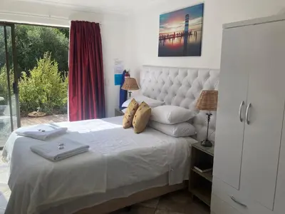 a bedroom with a white bed with two towels on it at Suikerbekkie in Somerset West