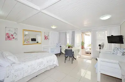 a bedroom with a bed and a desk and a table at Arum Field Accommodation in Table View