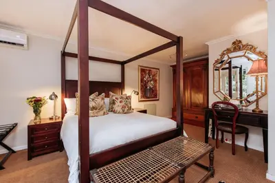 a bedroom with a canopy bed and a desk at Maison Chablis Guest House in Franschhoek