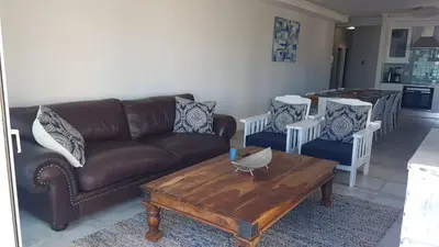 a living room with a couch and a table and chairs at 109 da Gama on Beach in Strand