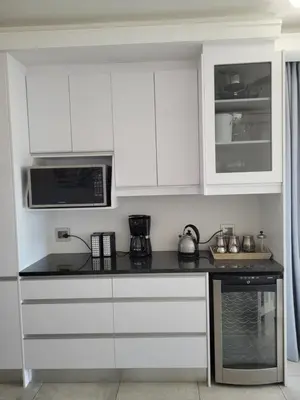a kitchen with white cabinets and a black counter top at 109 da Gama on Beach in Strand