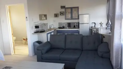 a living room with a couch and a kitchen at 29 Carissa Street in Somerset West