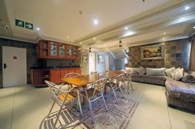 a kitchen and living room with a table and chairs at Savoy Lodge in Cape Town