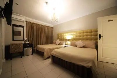 a hotel room with two beds and a chandelier at Savoy Lodge in Cape Town