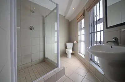 a bathroom with a shower and a sink and a toilet at Savoy Lodge in Cape Town