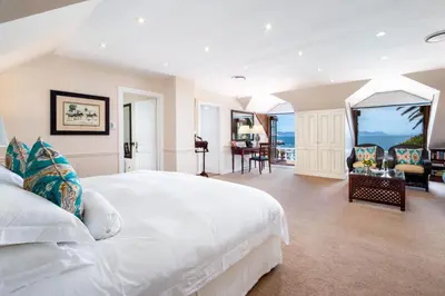 a bedroom with a white bed and a view of the ocean at La Fontaine Guest House Hermanus in Hermanus