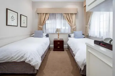 a bedroom with two beds and a window at La Fontaine Guest House Hermanus in Hermanus