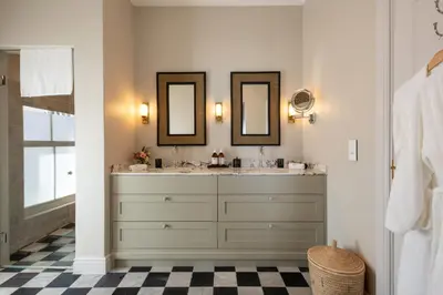 a bathroom with two sinks and two mirrors at La Fontaine Guest House Hermanus in Hermanus