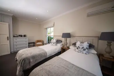 a bedroom with two beds and a window at Maison d'Ail Guest House in Franschhoek
