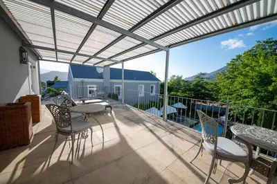 a patio with tables and chairs on a balcony at Maison d'Ail Guest House in Franschhoek