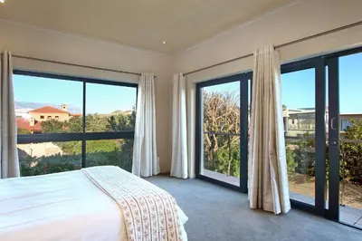 a bedroom with a bed and large windows at Sunset at Granula in Cape Town