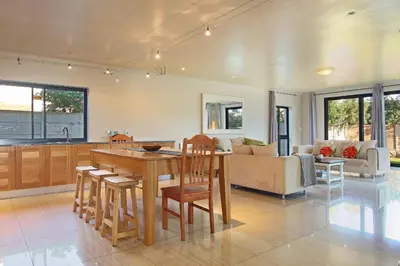 a kitchen and living room with a wooden table and chairs at Sunset at Granula in Cape Town
