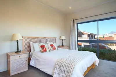 a bedroom with a bed and a large window at Sunset at Granula in Cape Town
