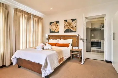a bedroom with a large bed with white sheets and orange pillows at Kwantu Guesthouse 2 in Cape Town