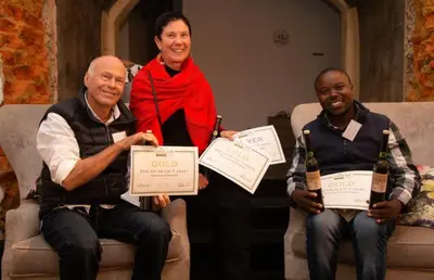 two men and a woman holding certificates and bottles of wine at Olive Hill Guest House in Robertson